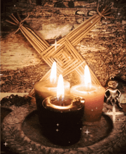 three candles are lit in front of a cross made of straw