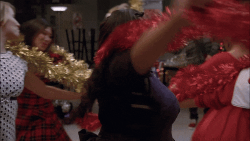 a cheerleader in a purple top is holding red pom poms