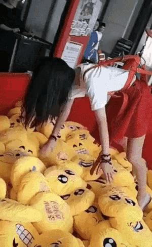 a woman is playing with a pile of stuffed smiley faces including one that says coca cola