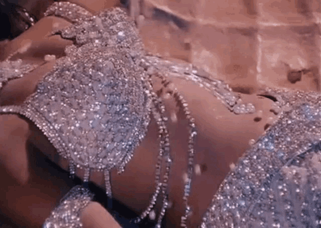 a woman is laying on a bed wearing a very shiny bra