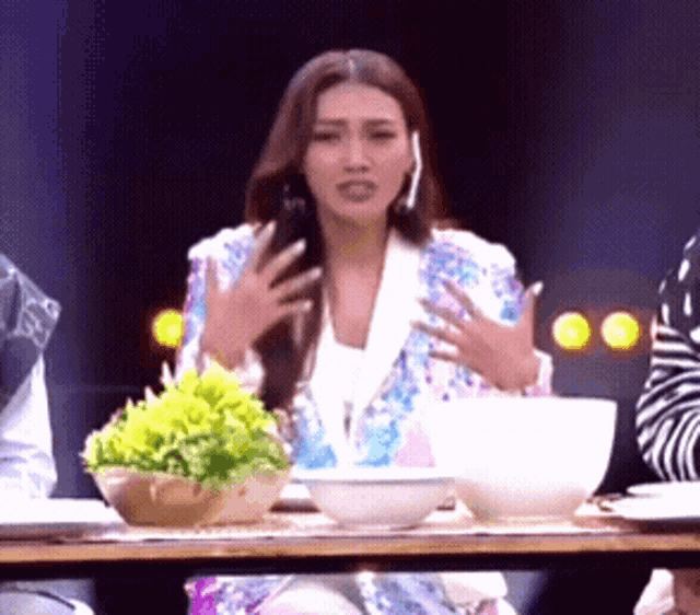 a woman sitting at a table with bowls and plates