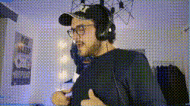 a man wearing headphones and a baseball cap is playing a video game in a room .
