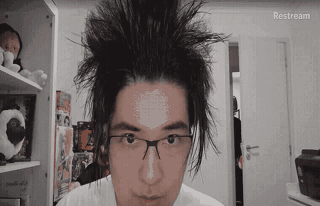 a man with messy hair and glasses looks at the camera with the word restream visible in the corner