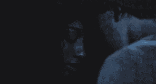 a close up of a man and woman 's faces in a dark room