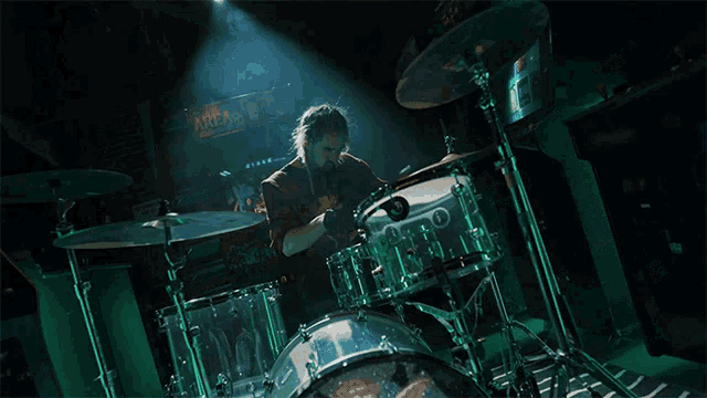 a man playing drums with a sign in the background that says area