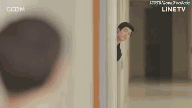a man peeking out from behind a wall with ccdm on the bottom