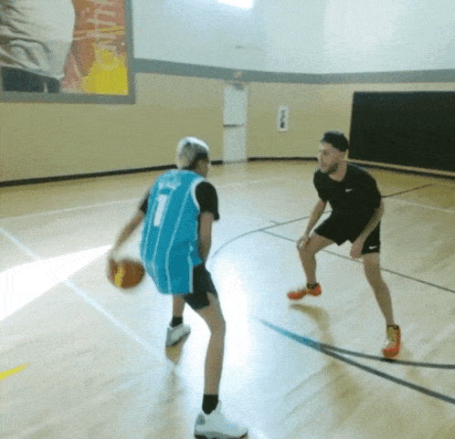 a man in a blue jersey with the number 1 on it dribbles a basketball
