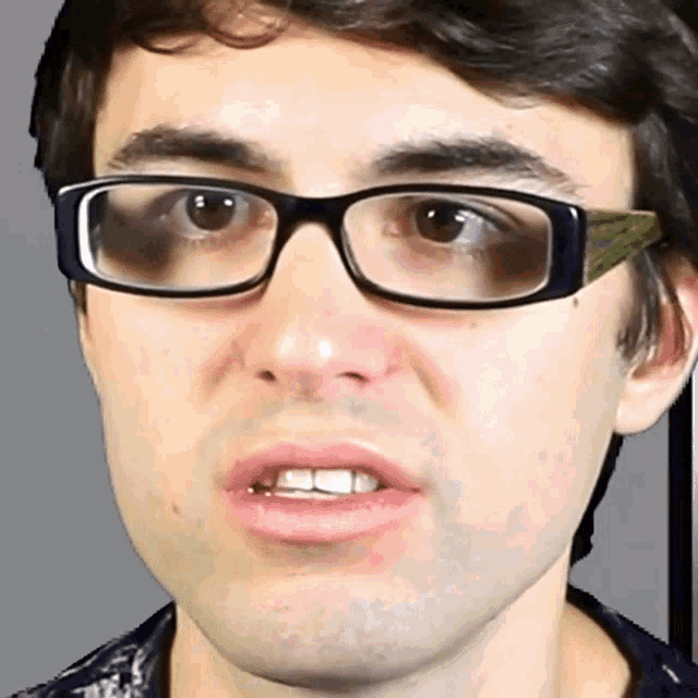 a close up of a man wearing glasses and making a face