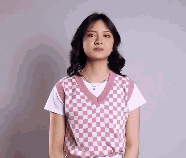 a girl wearing a pink and white checkered vest and a white shirt
