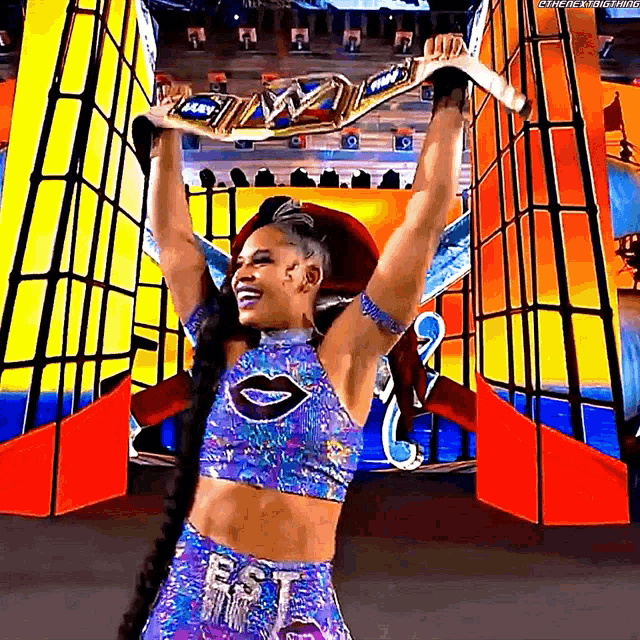 a female wrestler is holding a championship belt over her head .