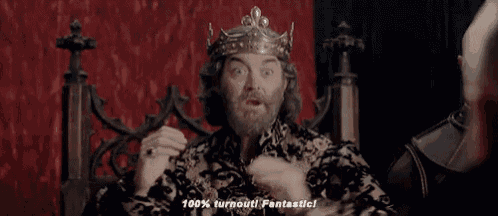 a man with a beard wearing a crown is sitting on a throne and making a funny face .