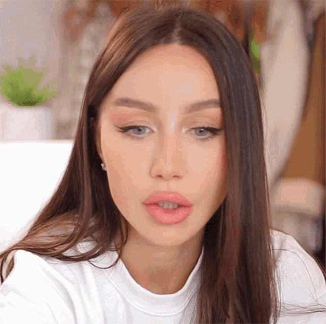 a woman with long dark hair is wearing a white shirt and looking at the camera
