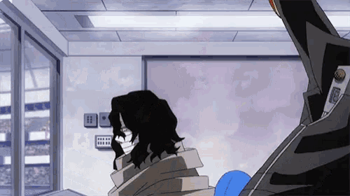 a man with long black hair is standing in a room with a blue blanket .