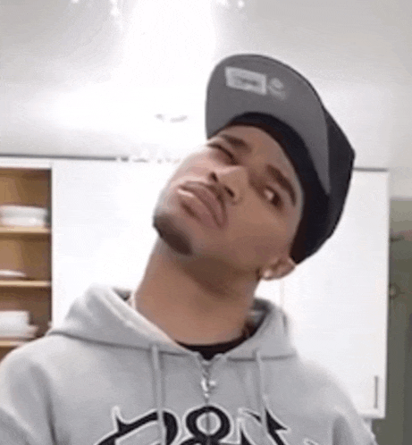 a man wearing a hat and a hoodie is looking up at something