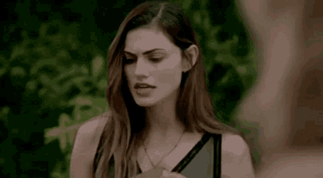 a woman is standing in front of a tree and looking at a man .