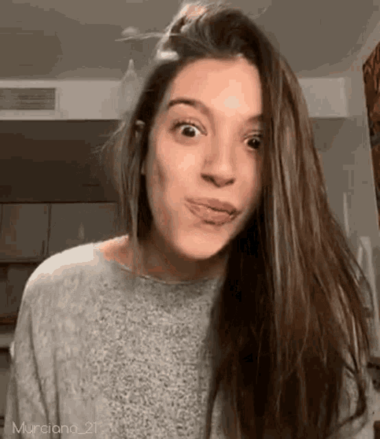 a woman with long brown hair is making a funny face .