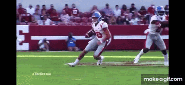 a football player is running with the ball while another player tries to stop him .