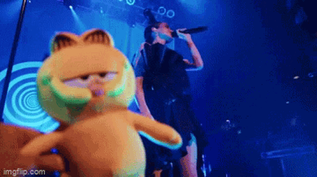 a woman singing into a microphone while garfield looks on