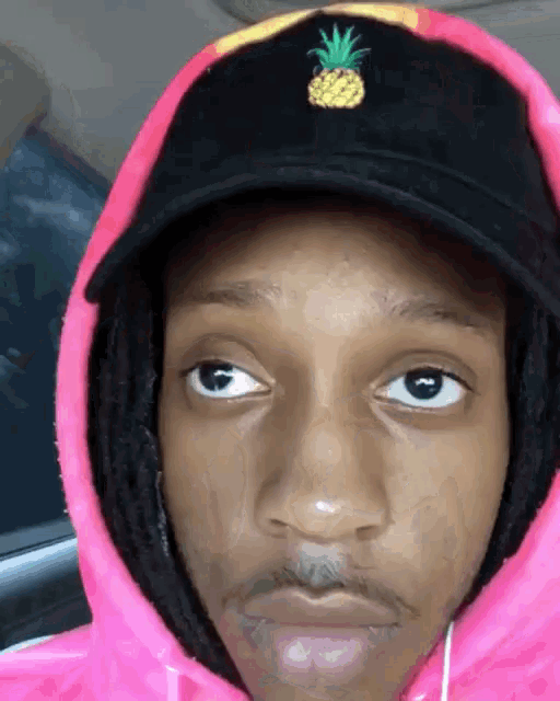 a person wearing a pink hoodie and a pineapple hat