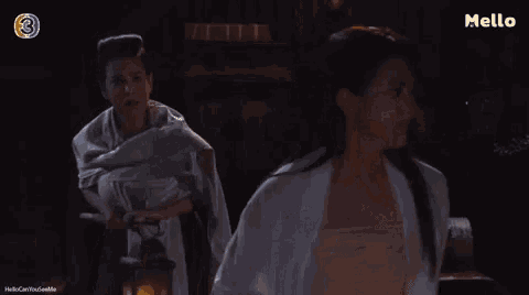 two women are standing next to each other in a dark room in front of a lantern .