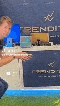 a man stands in front of a trendit sign