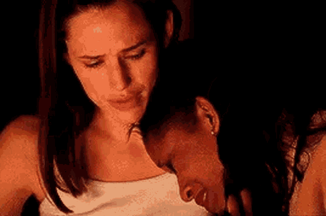 two women are hugging each other in a dark room and one of them is crying .