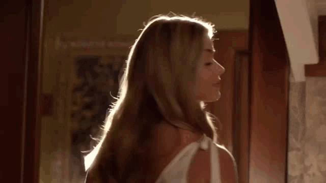 a woman in a white dress is standing in a doorway and looking over her shoulder .