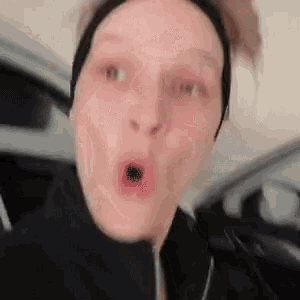 a close up of a woman making a funny face while sitting in a car .