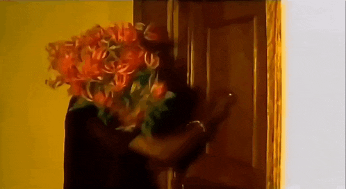 a woman holding a bouquet of orange flowers in front of her face