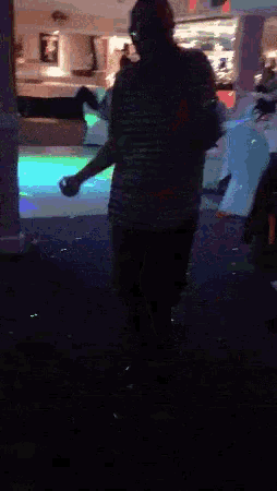 a man dancing in a dark room with a red exit sign