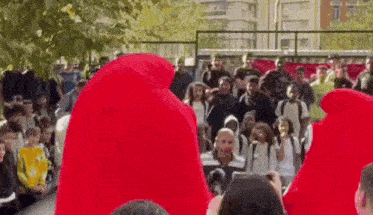 a group of people wearing red hoodies are standing in front of a crowd of people .
