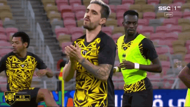 a soccer player wearing a yellow and black jersey with the number 77 on it
