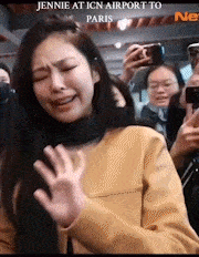 a woman in a yellow sweater is standing in front of a crowd .