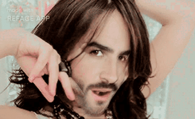 a man with long hair and a beard talking on a cell phone .
