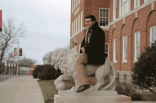 a man sits on the back of a lion statue