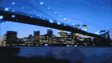 a blurry picture of a bridge over a body of water with a city in the background