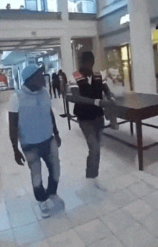 a man in a blue vest is walking in a mall with another man