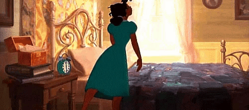 a woman in a green dress is standing in front of a bed in a bedroom .