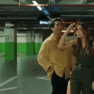 a man and a woman are standing in a parking garage with a sign that says " cikup " on it