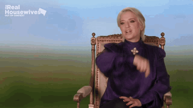 a woman in a purple shirt sits in a chair with the words real housewives out of context behind her