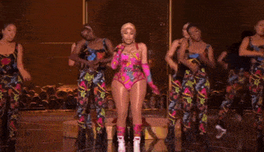 a group of dancers are performing on a stage with a crown in the middle