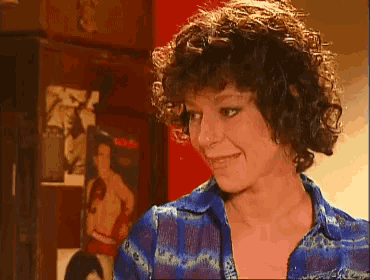 a woman with curly hair is smiling in front of a picture of a boxer