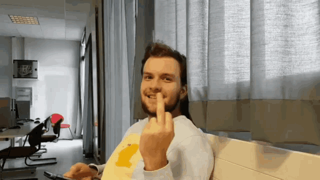 a man wearing a yellow shirt with a duck on it giving the middle finger