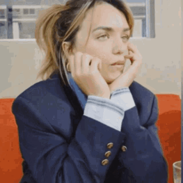 a woman in a suit is sitting on a red couch