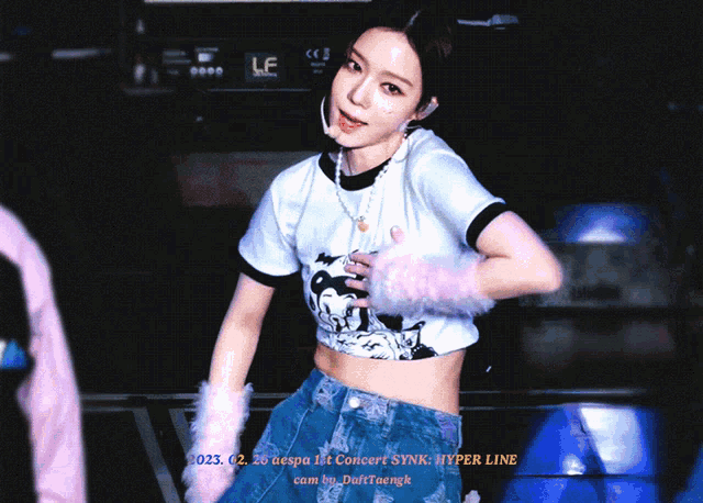 a woman wearing a crop top with a mickey mouse on it is standing in front of a sign that says hyper line
