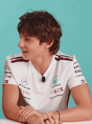 a man wearing a white shirt with sponsors on the sleeves