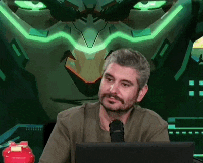 a man is sitting in front of a computer with a robot in the background behind him .