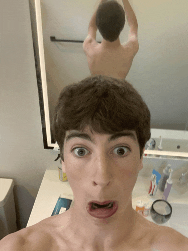 a young man making a funny face in front of a mirror