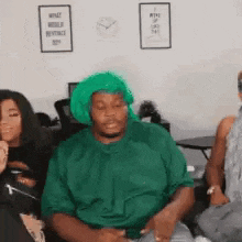 a man wearing a green turban is sitting on a couch with other people .
