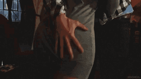 a man is touching a woman 's butt with his hand in a dark room .